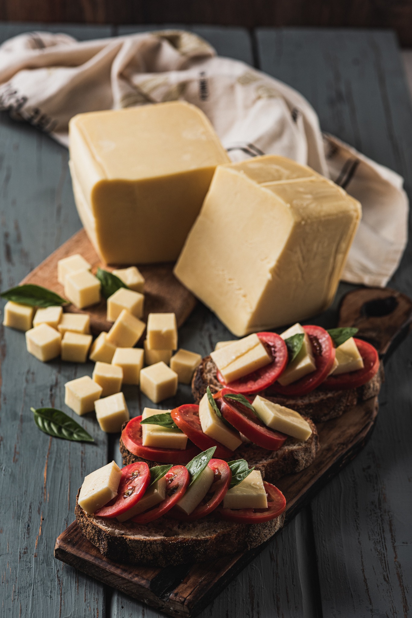 Bocados de queso, tomate y aceitunas sobre una tabla